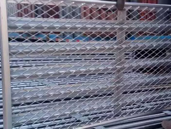 Workers are carrying many expanded metal gratings into the container.